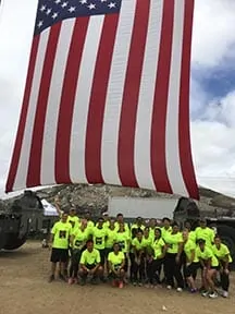 SCS Engineers team participating in a mud run at Camp Pendleton to support Marine Corps Community Services, showing the group muddy and cheerful after the event.
